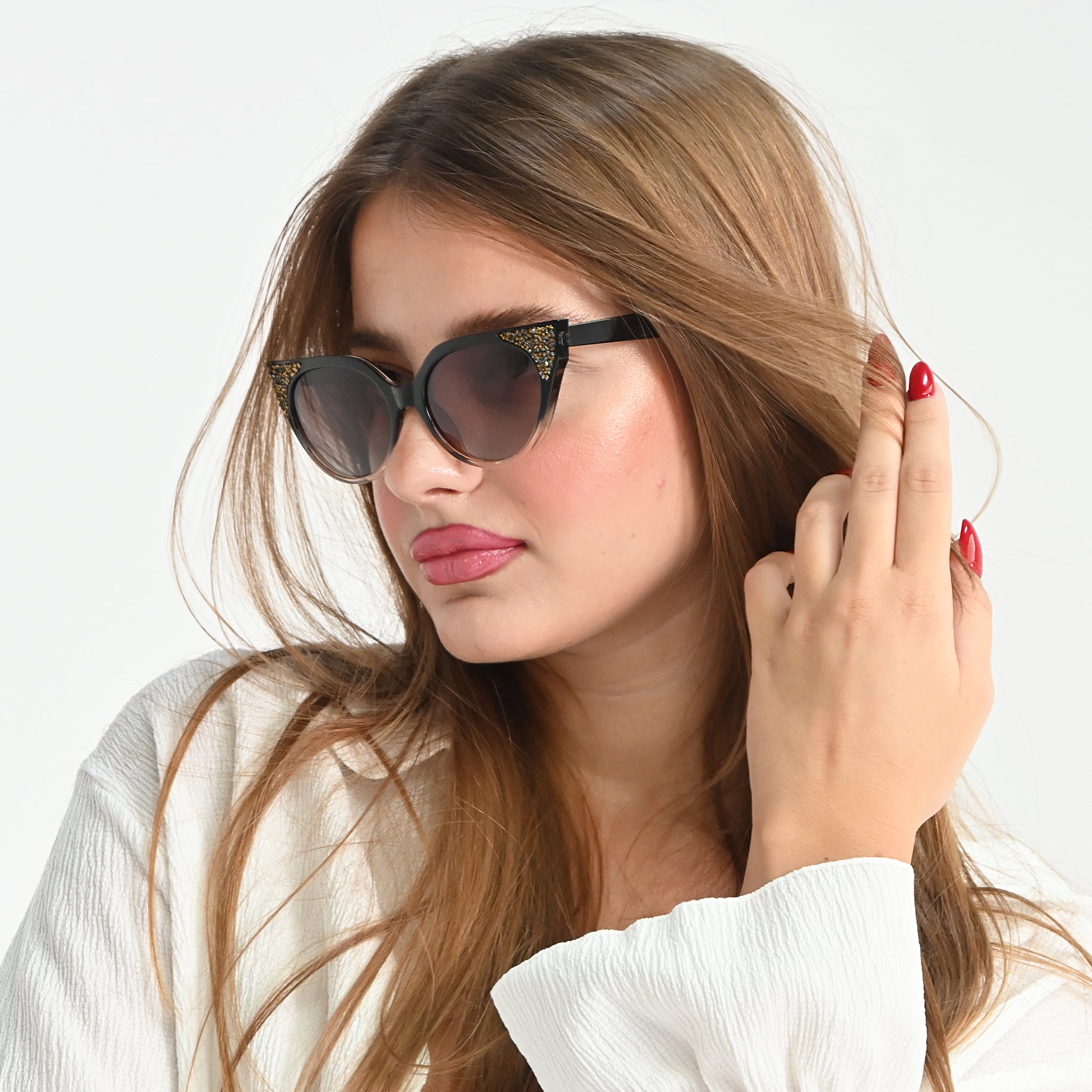 Woman wearing cat-eye sunglasses with a neutral background