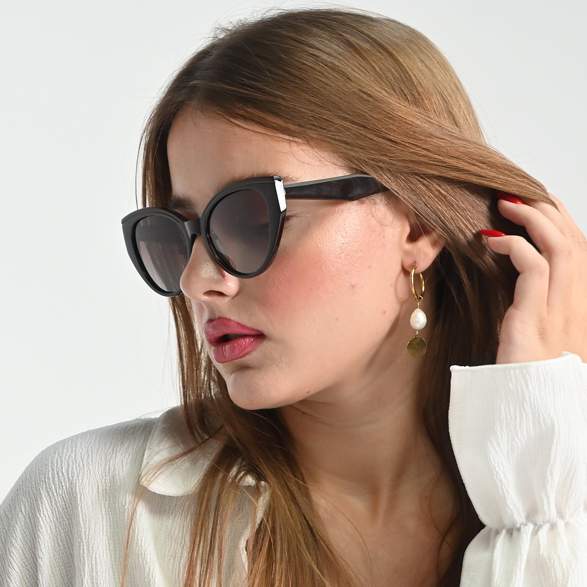 Woman wearing sunglasses and a white blouse with a plain background