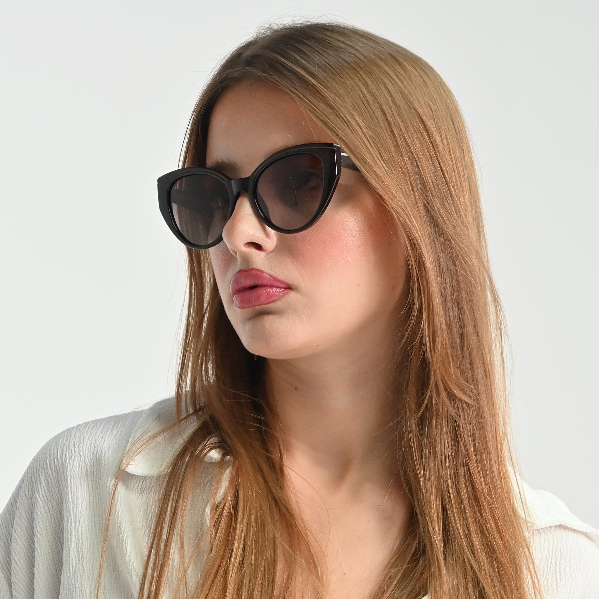 Woman wearing black cat-eye sunglasses against a white background
