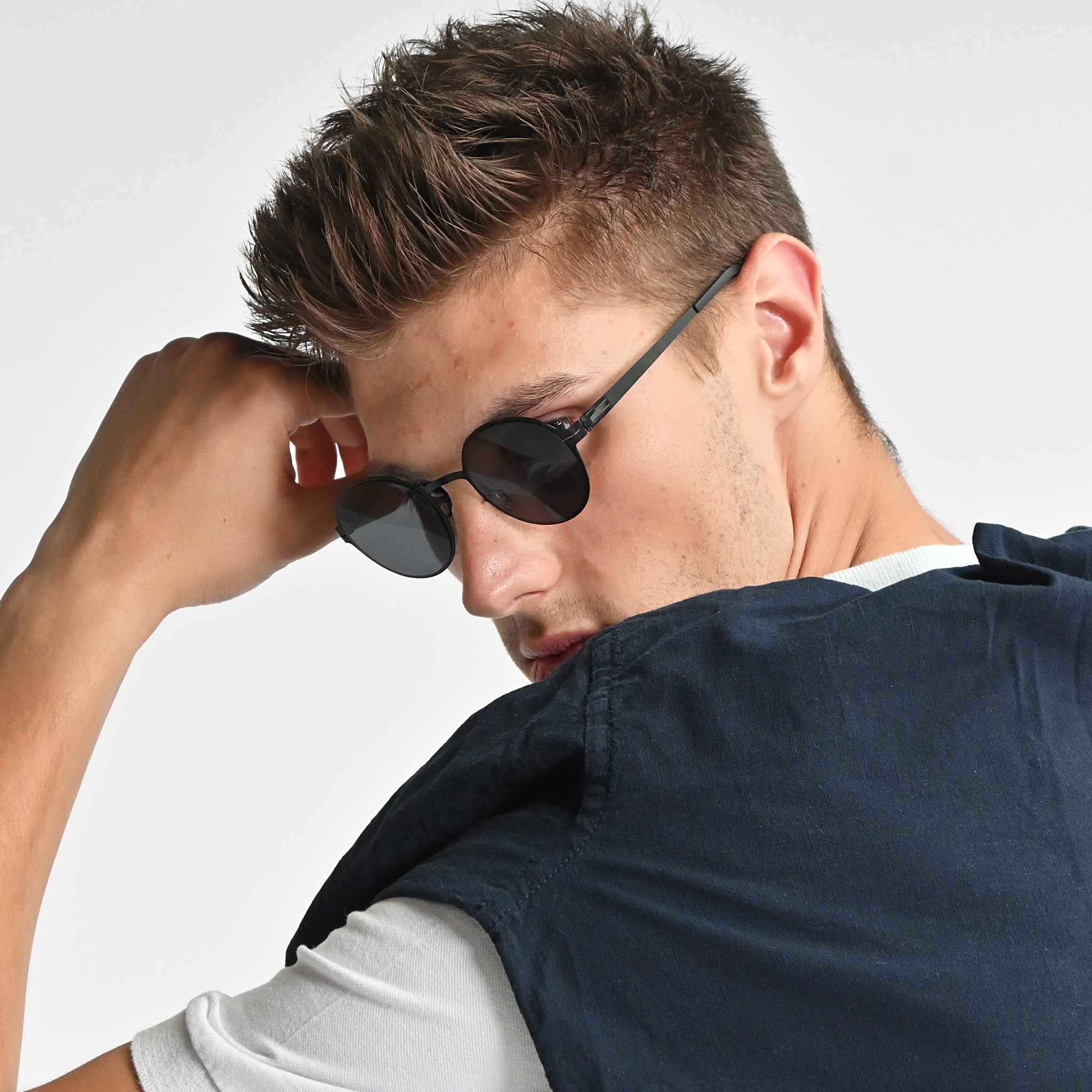 Man wearing sunglasses and a dark jacket on a white background