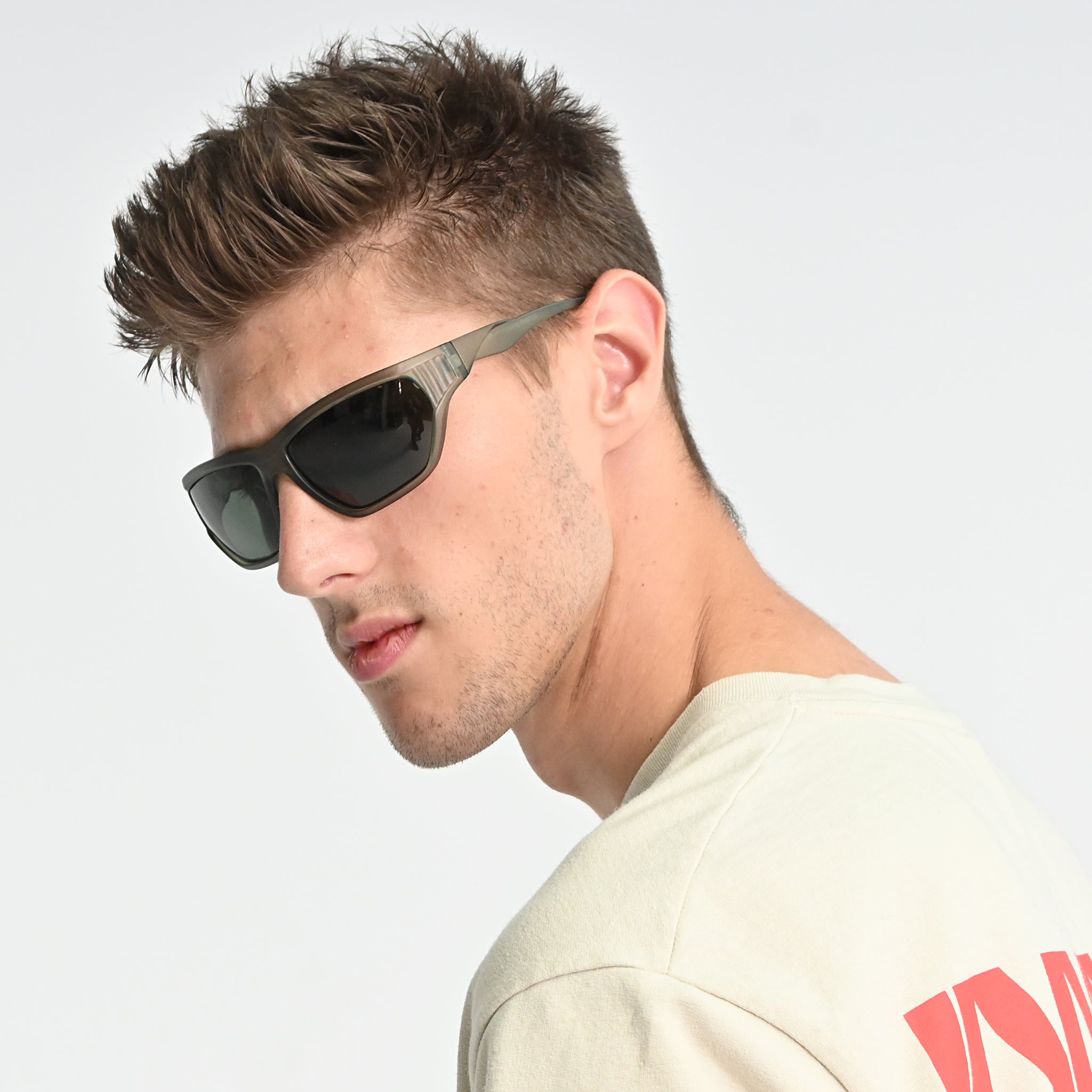 Man wearing sunglasses and a light-colored shirt with red text on a plain background