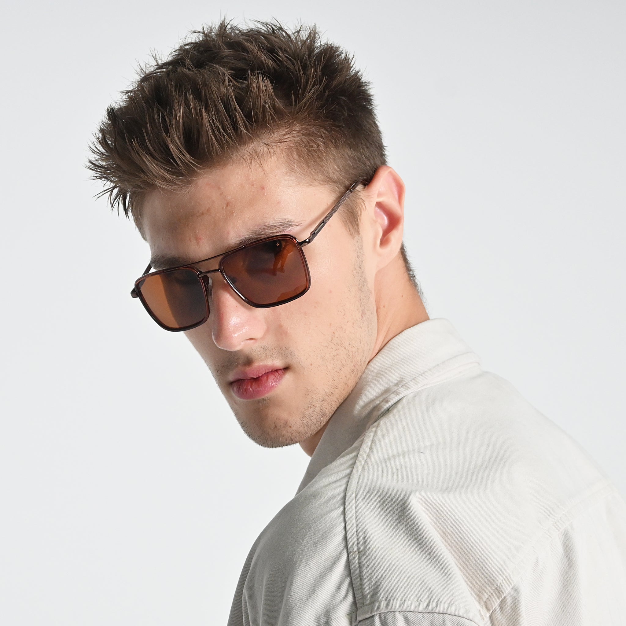 Man wearing sunglasses and a light-colored shirt against a plain background