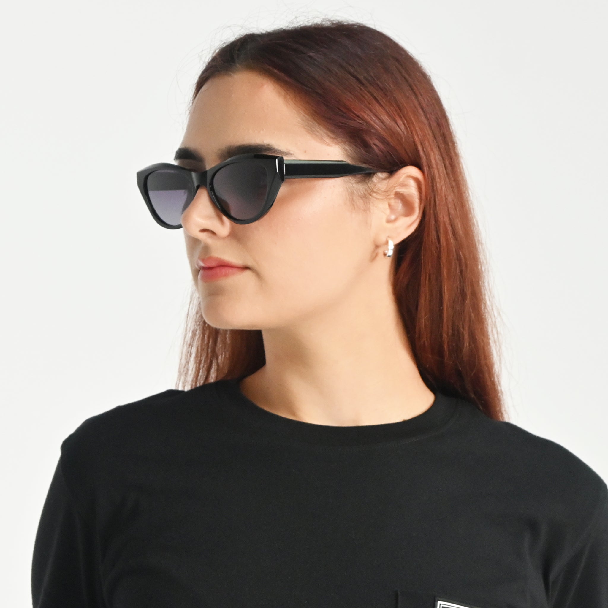Woman wearing black sunglasses and a black shirt on a white background