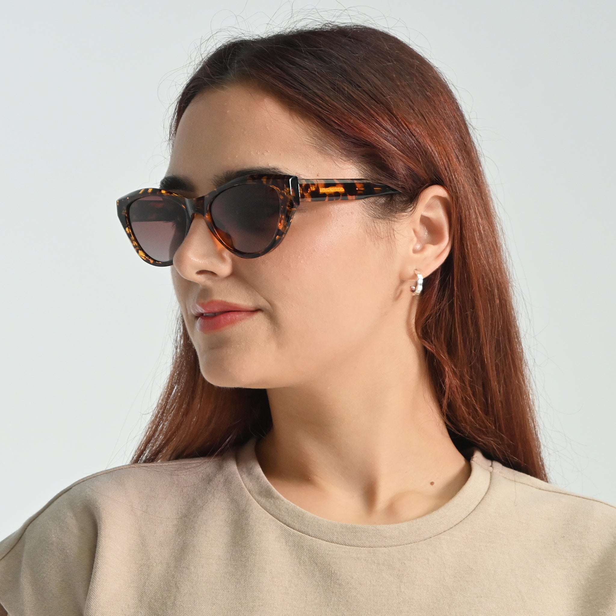 Woman wearing tortoiseshell sunglasses against a light gray background