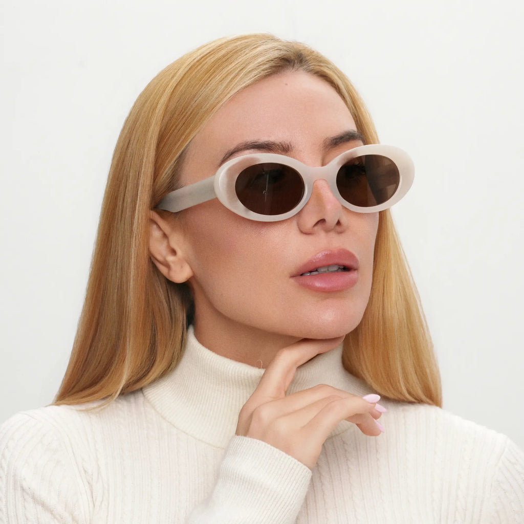 Woman wearing white sunglasses with a neutral background