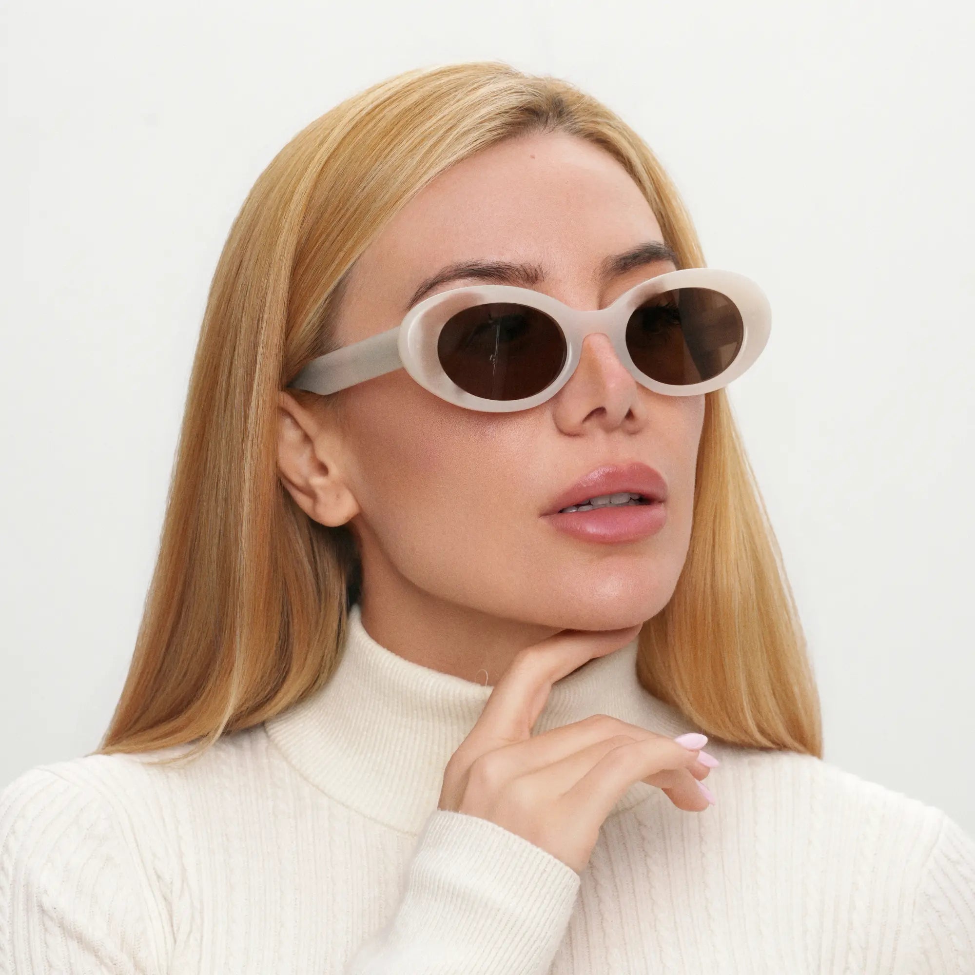 Woman wearing white sunglasses with a neutral background