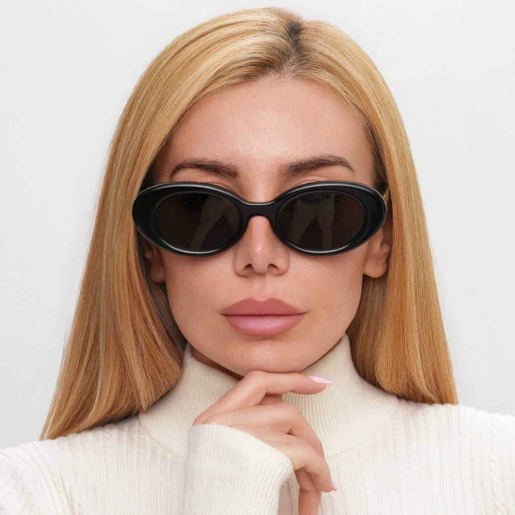 Woman wearing black sunglasses with a neutral background
