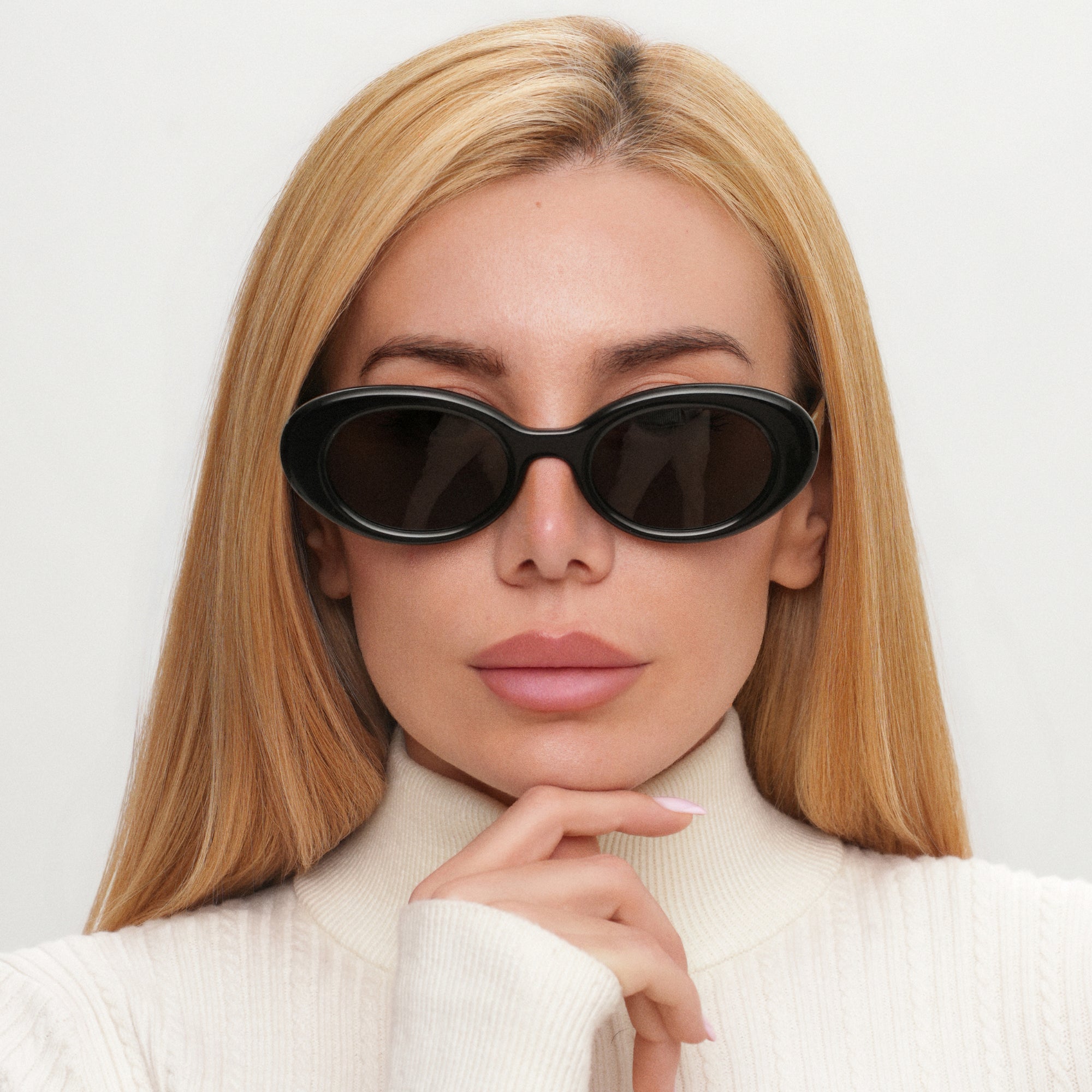 Woman wearing black sunglasses with a neutral background
