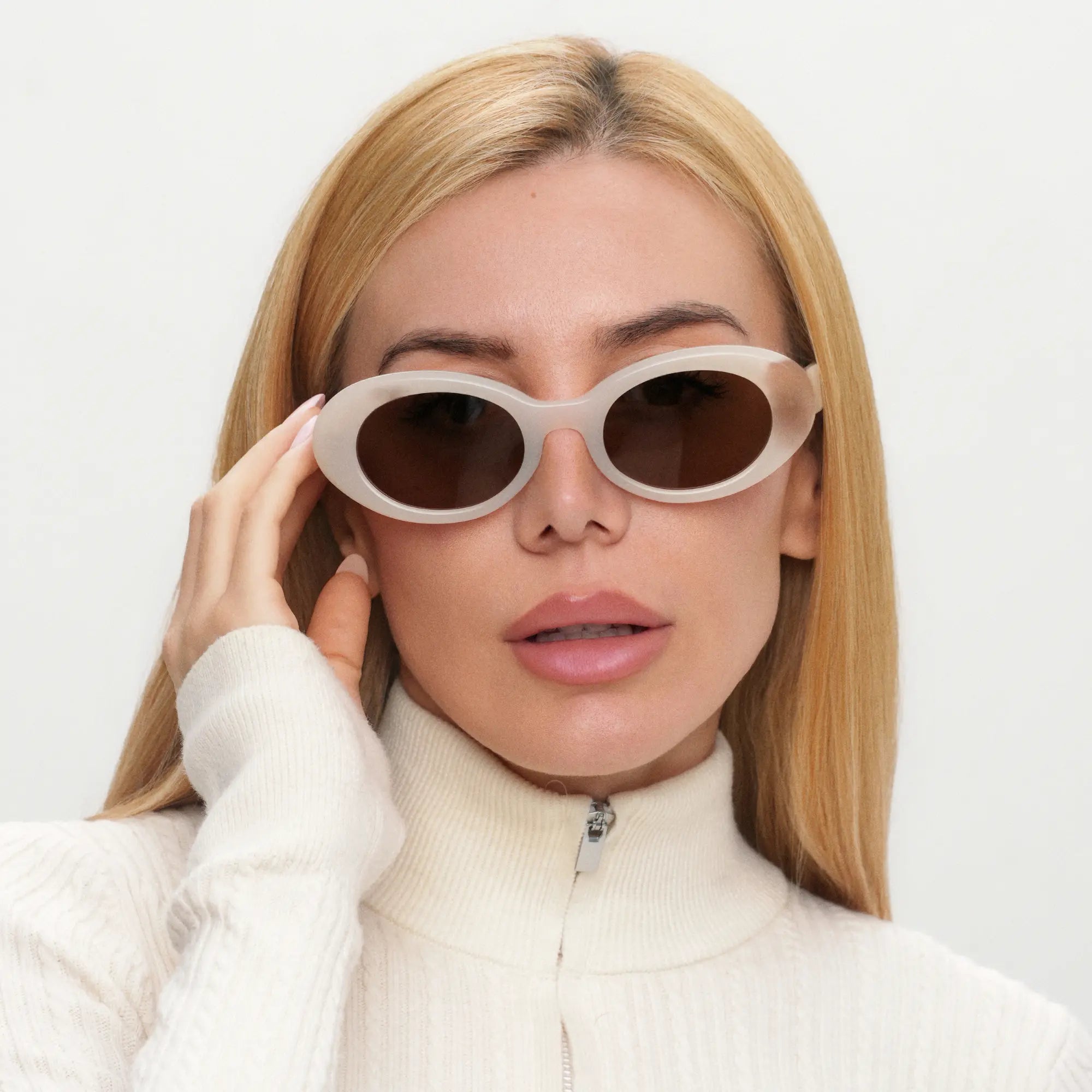 Woman wearing a pair of sunglasses with a plain background