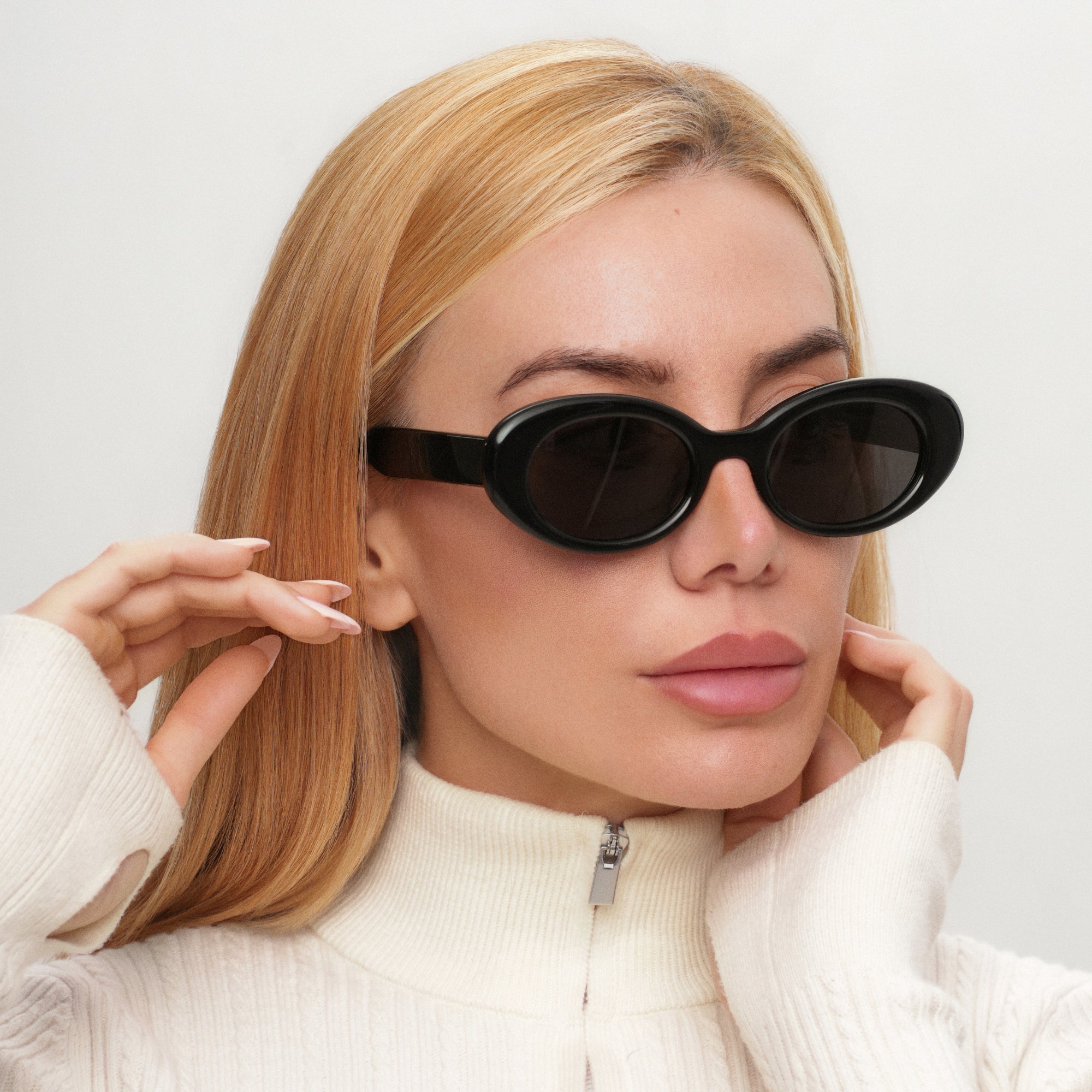 Woman wearing black cat-eye sunglasses against a light background