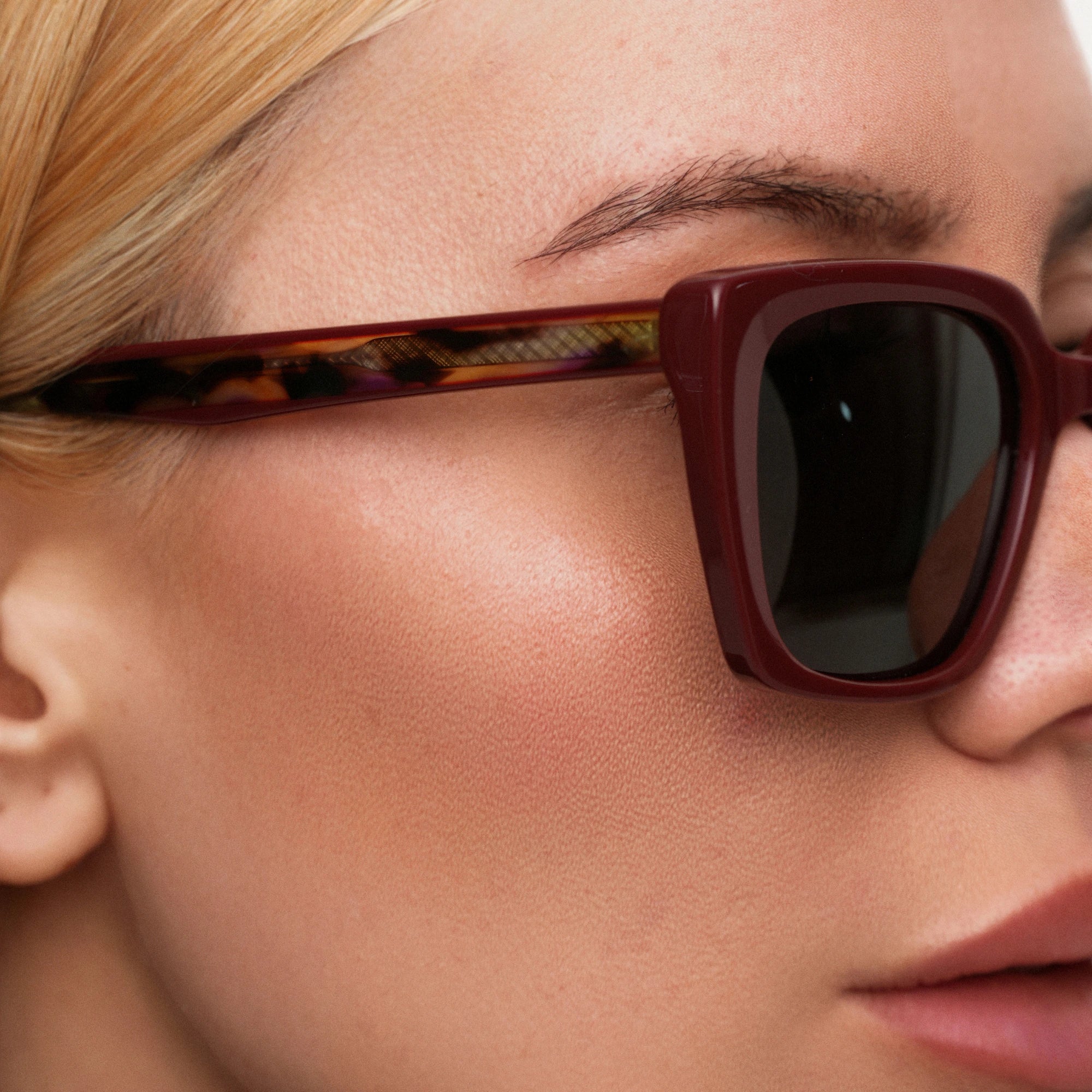 Close-up of a person wearing sunglasses with a tortoiseshell frame.
