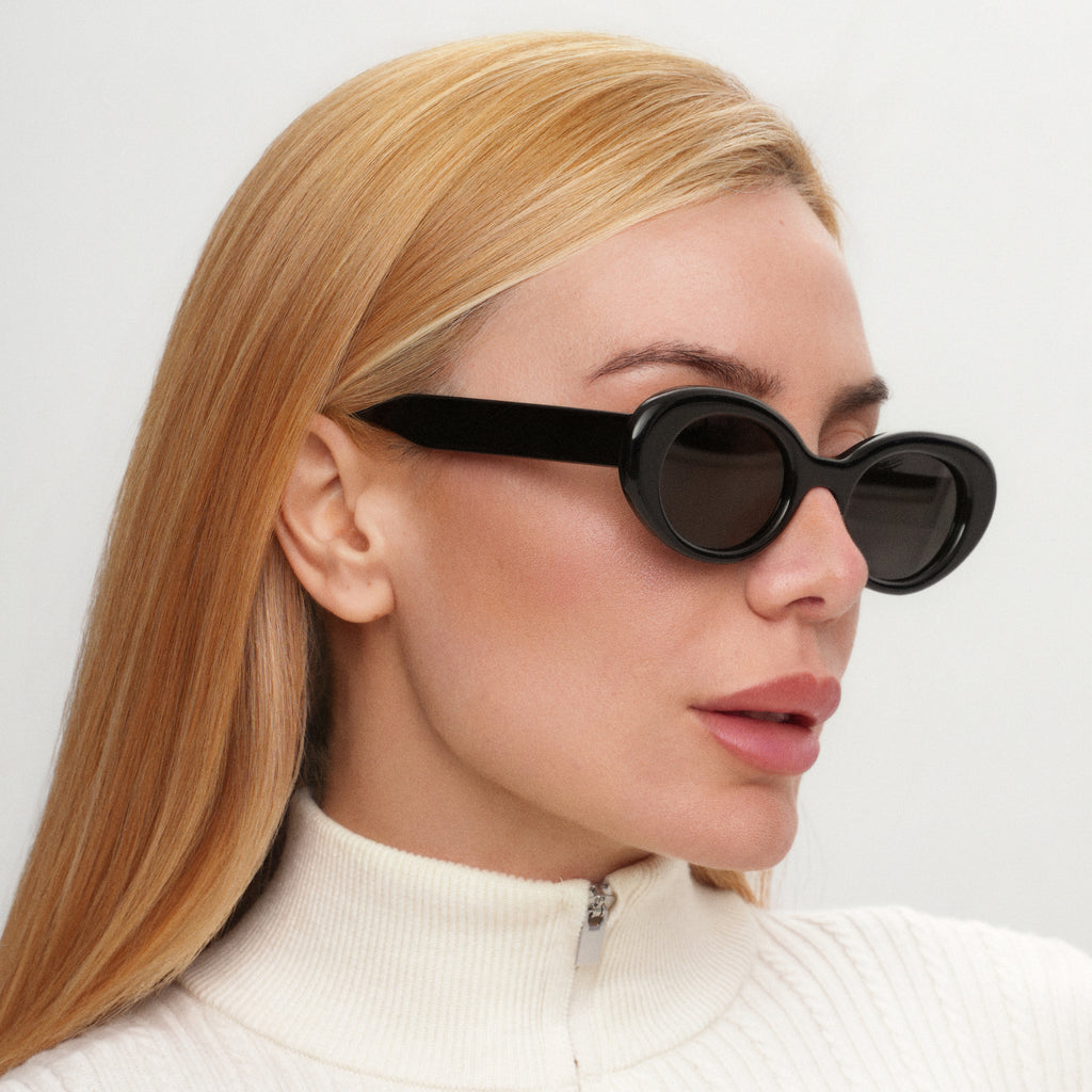 Woman wearing black sunglasses with a plain background
