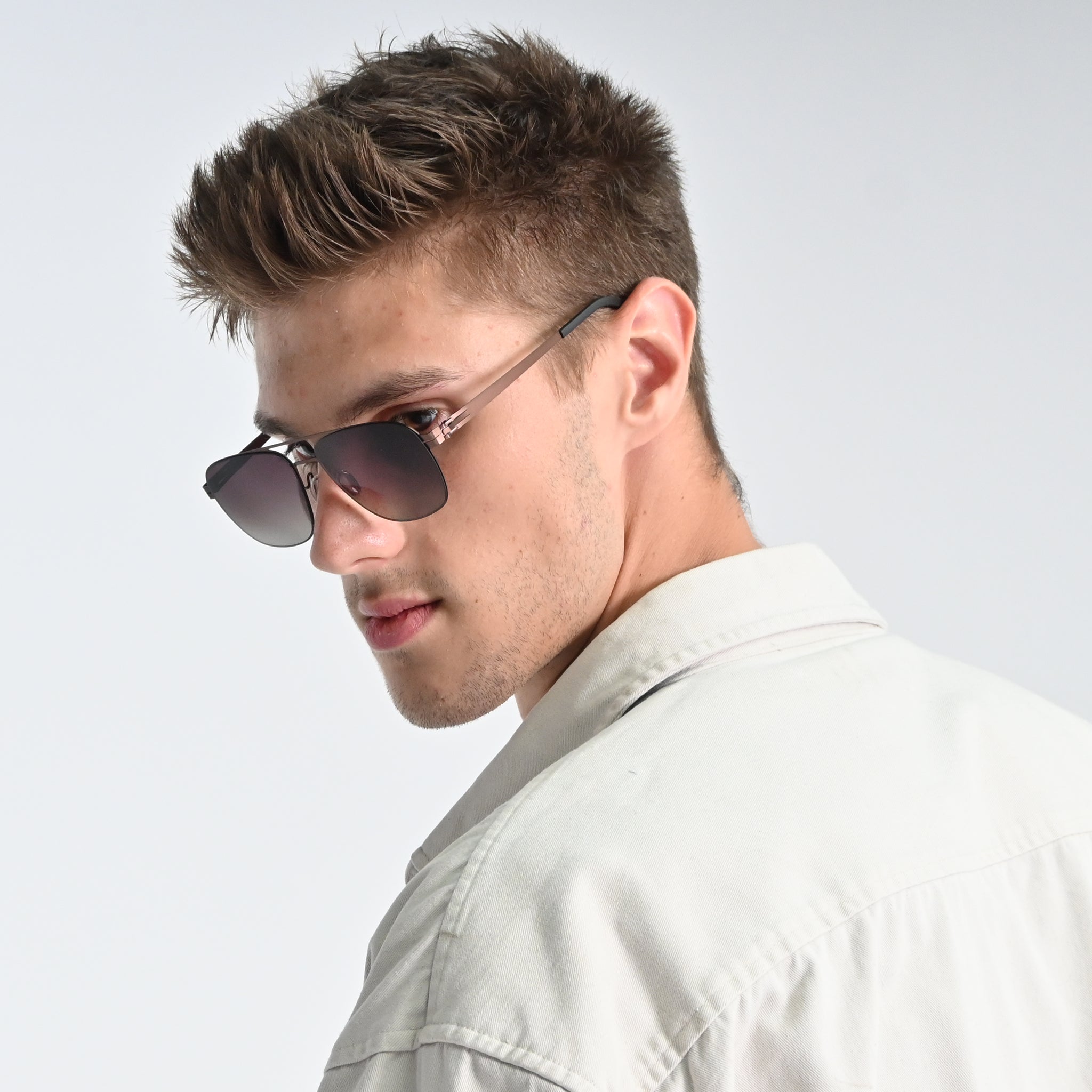 Man wearing sunglasses and a light-colored shirt against a plain background
