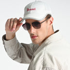 Man wearing a white cap with 'Perazzi' logo and sunglasses on a light gray background