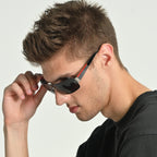 Man adjusting sunglasses on a plain background