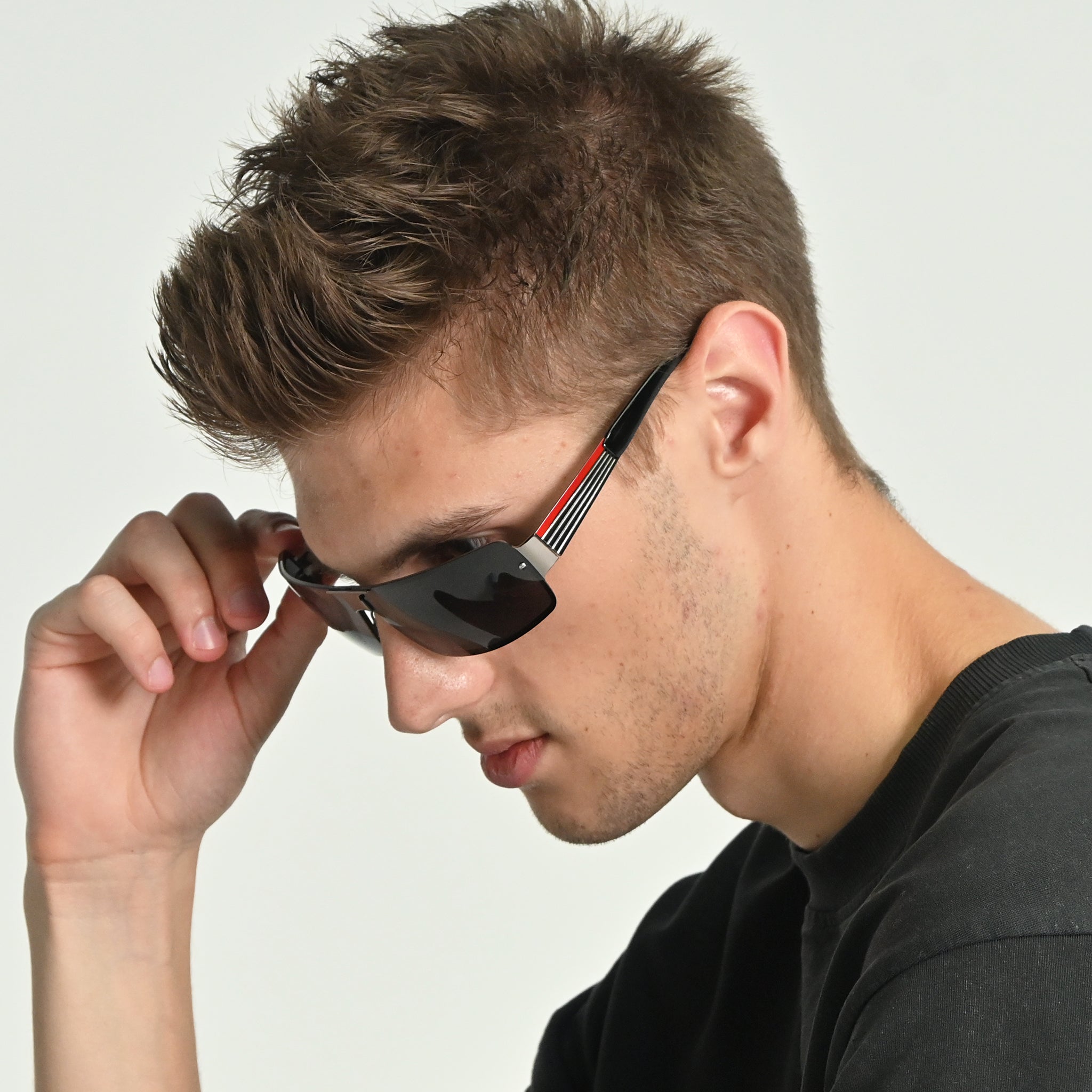 Man adjusting sunglasses on a plain background