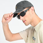 Man wearing a gray baseball cap and black sunglasses on a light gray background