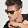 Man wearing black sunglasses with a neutral background