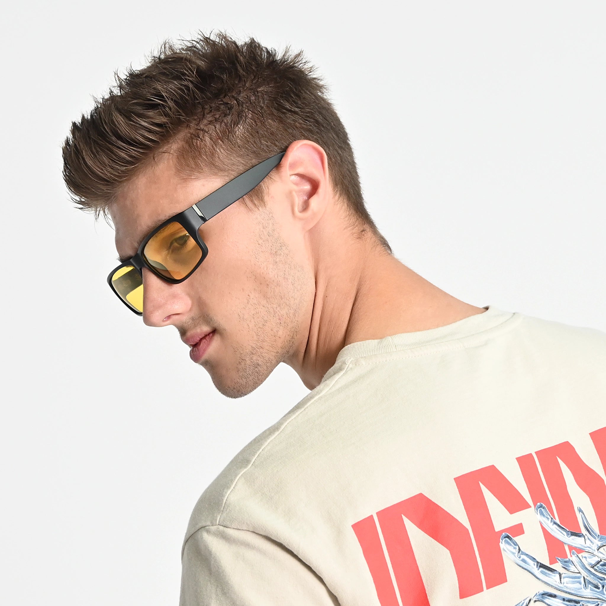 Man wearing sunglasses and a beige t-shirt with red text and graphics on a light gray background