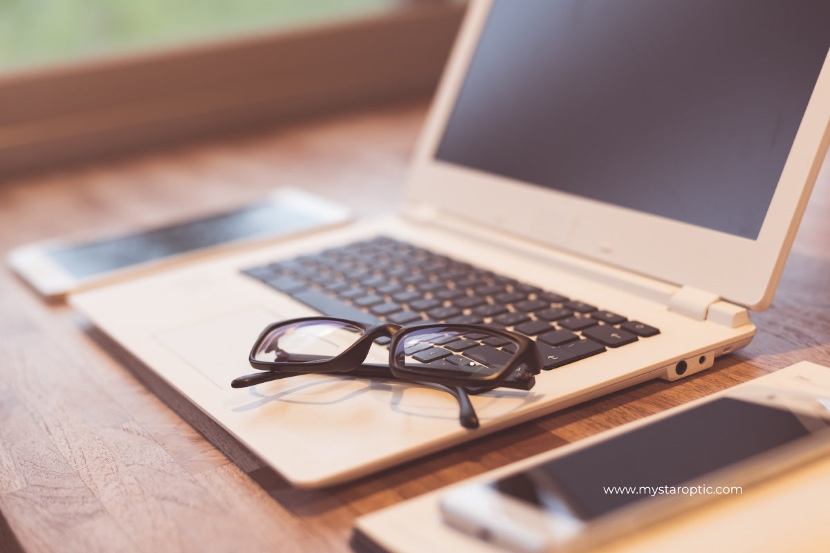 Laptop with eyeglasses on a wooden surface, blurred background