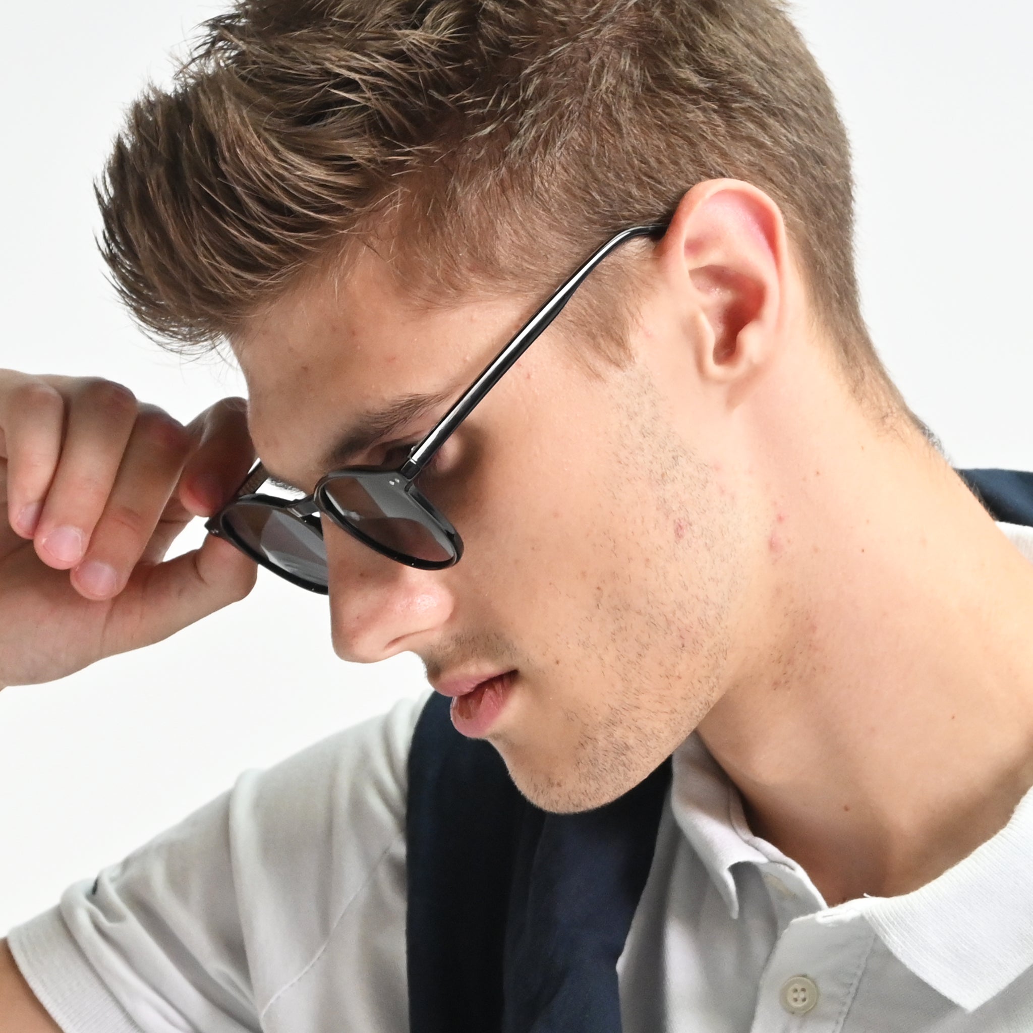 Man adjusting sunglasses on a white background