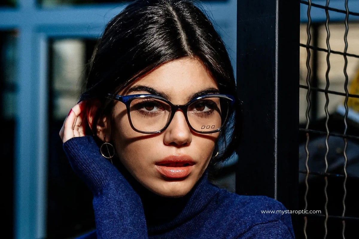 Model wearing stylish blue prescription glasses and a blue turtleneck, featured in MyStar Optic eyewear campaign.