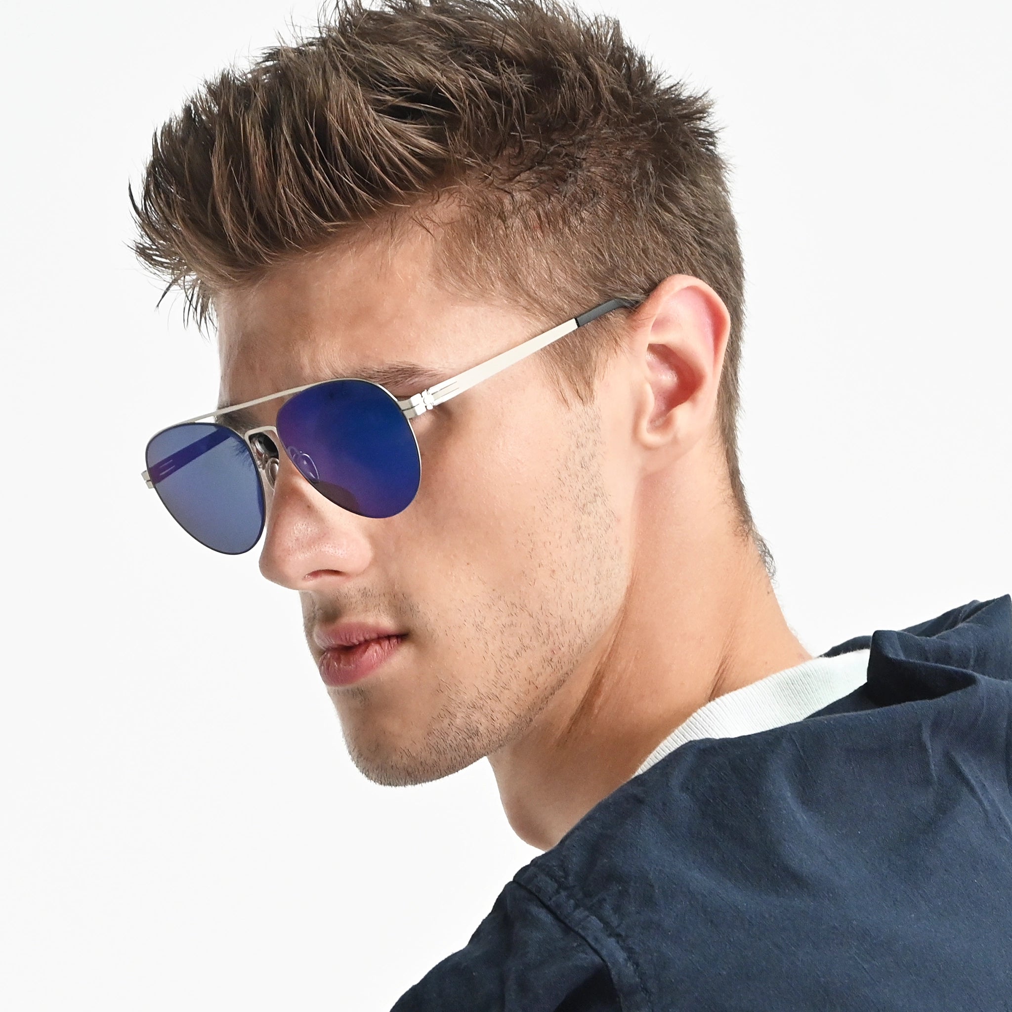 Man wearing blue reflective sunglasses with a neutral background