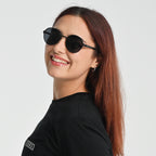 Woman wearing black sunglasses and a black shirt with a logo on a light gray background