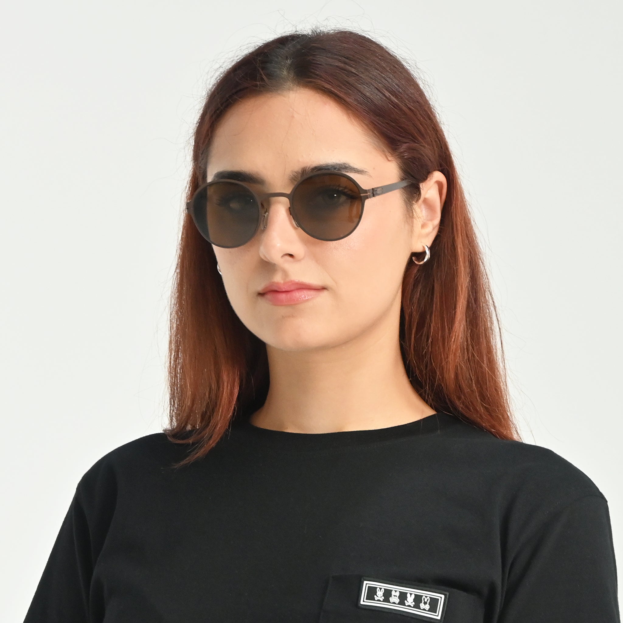 Woman wearing round sunglasses with a plain background