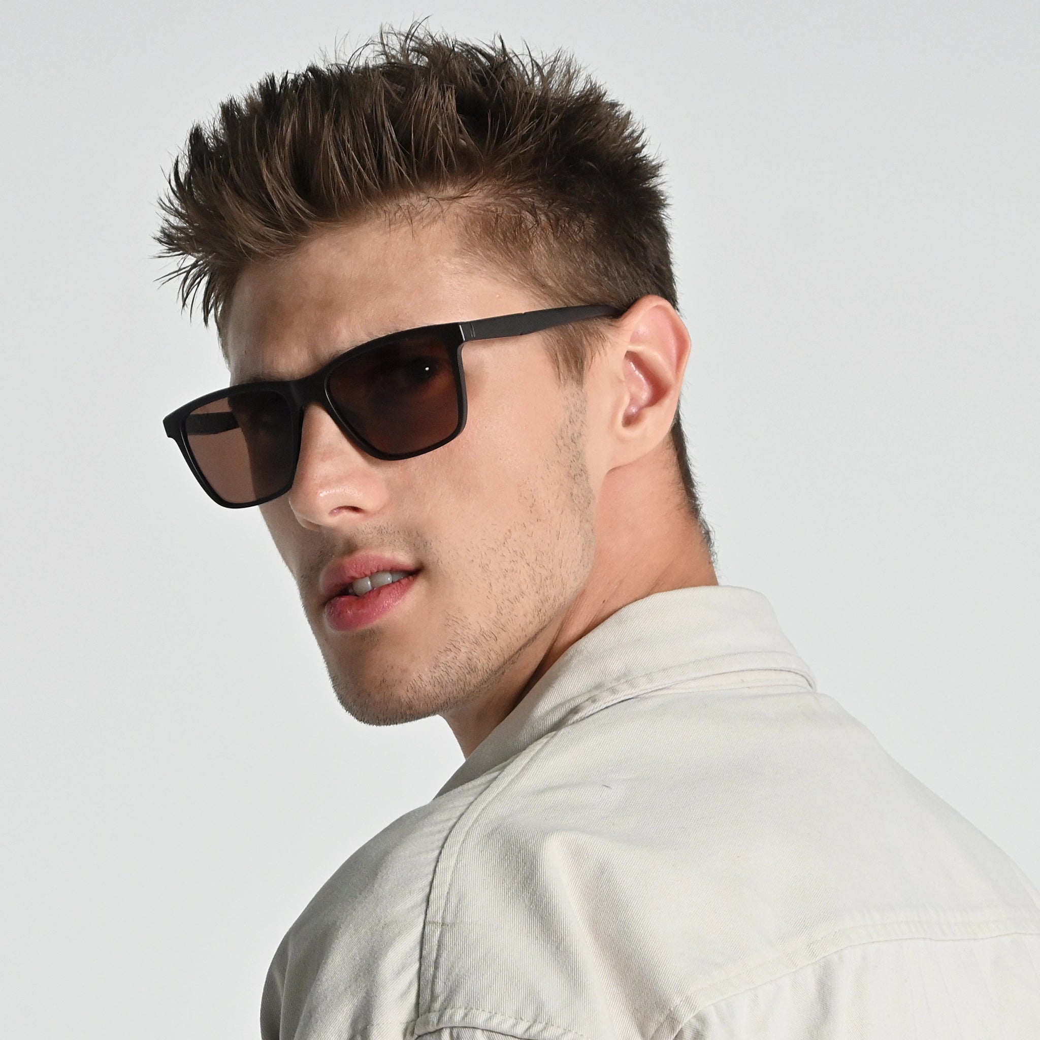 Man wearing sunglasses and a light-colored shirt against a plain background