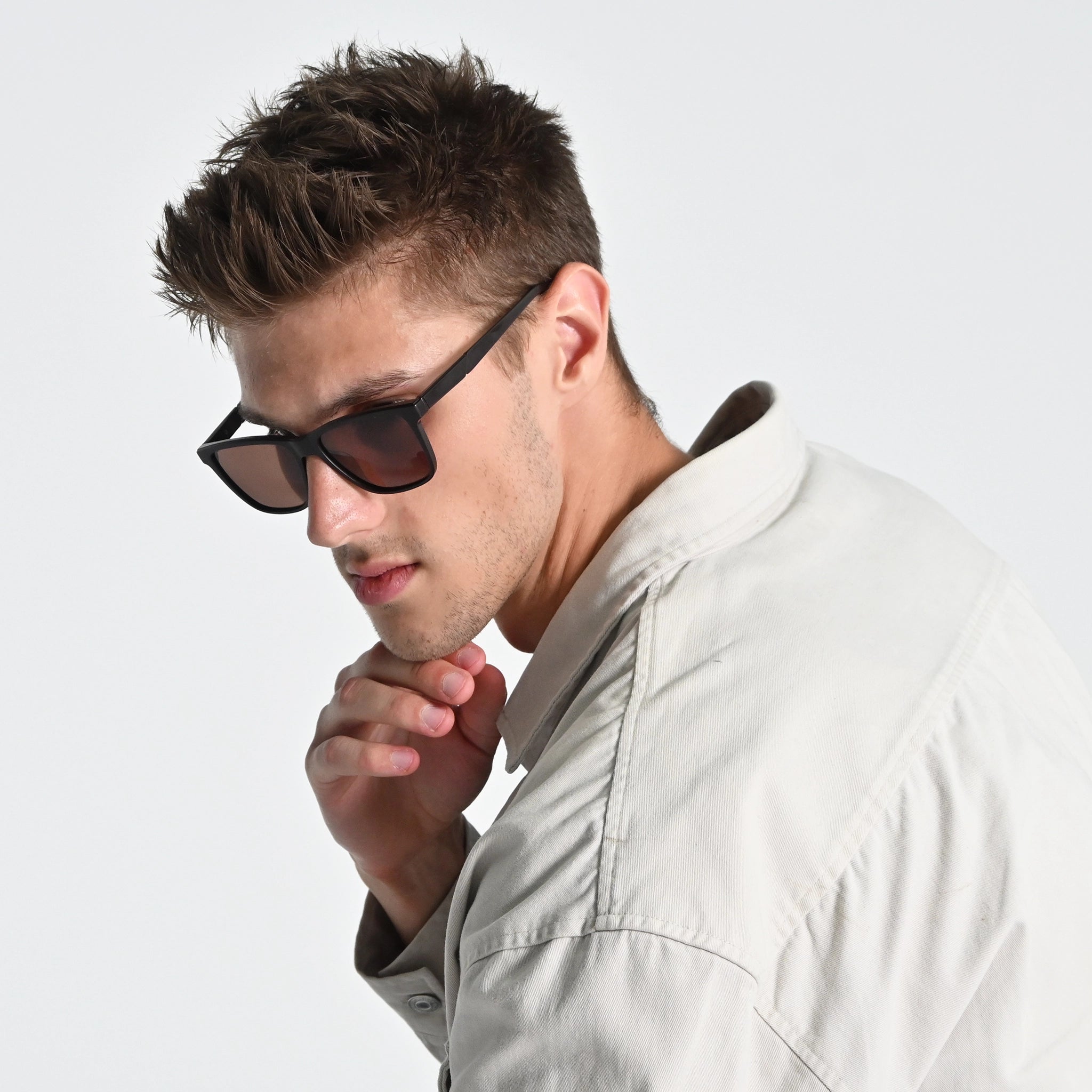 Man wearing sunglasses and a light-colored shirt against a plain background