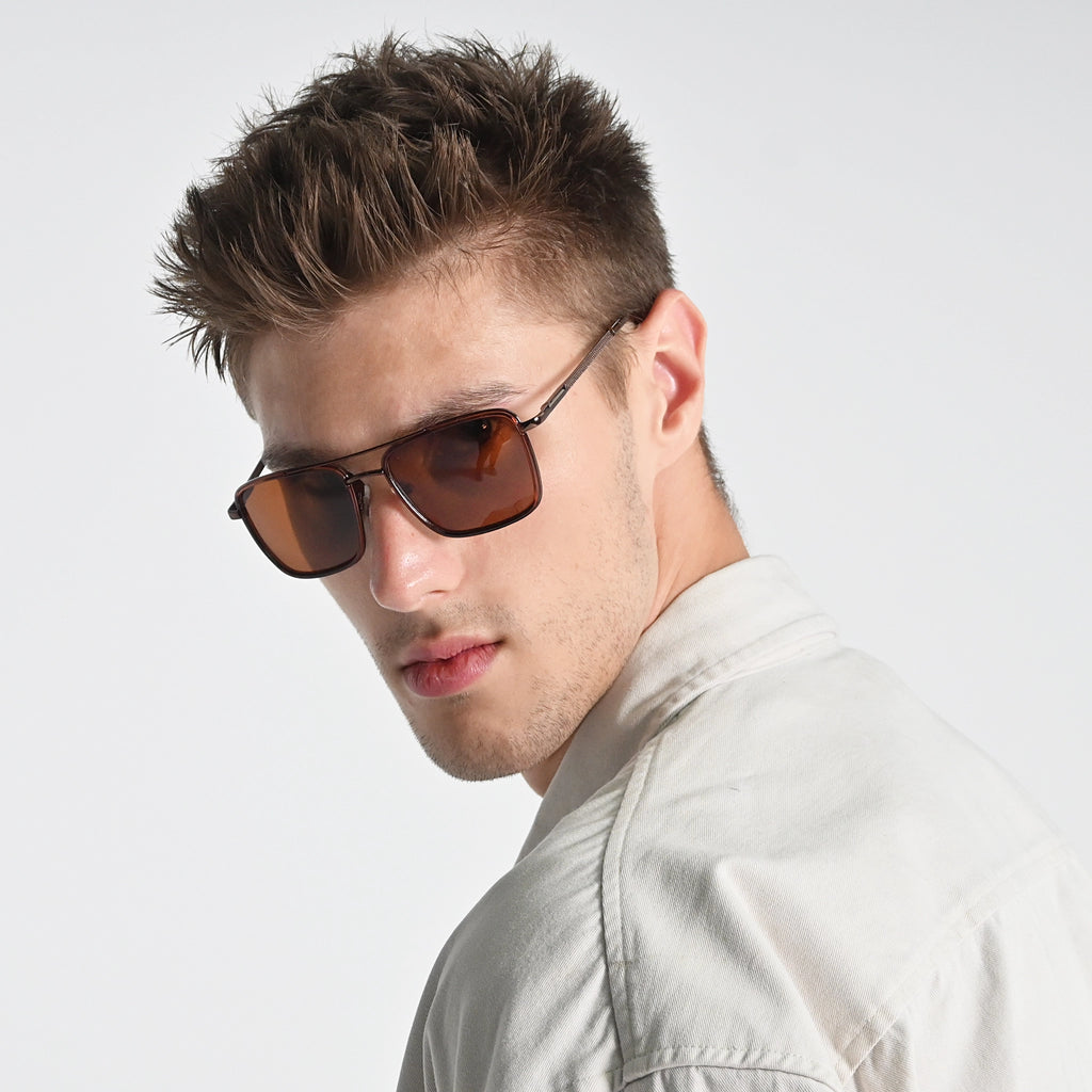 Man wearing sunglasses and a light-colored shirt against a plain background