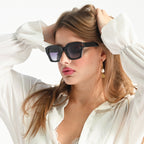Woman wearing sunglasses and a white blouse with a plain background