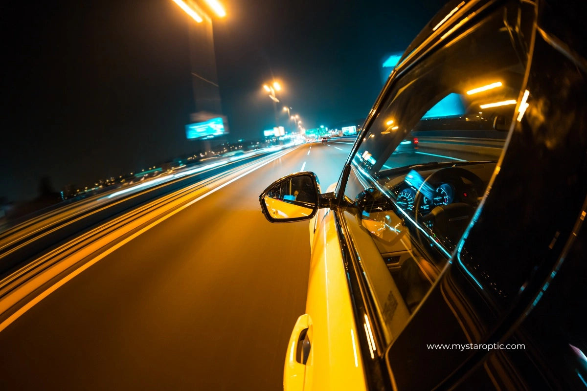 Car driving on a highway at night with reflections on the car's surface.