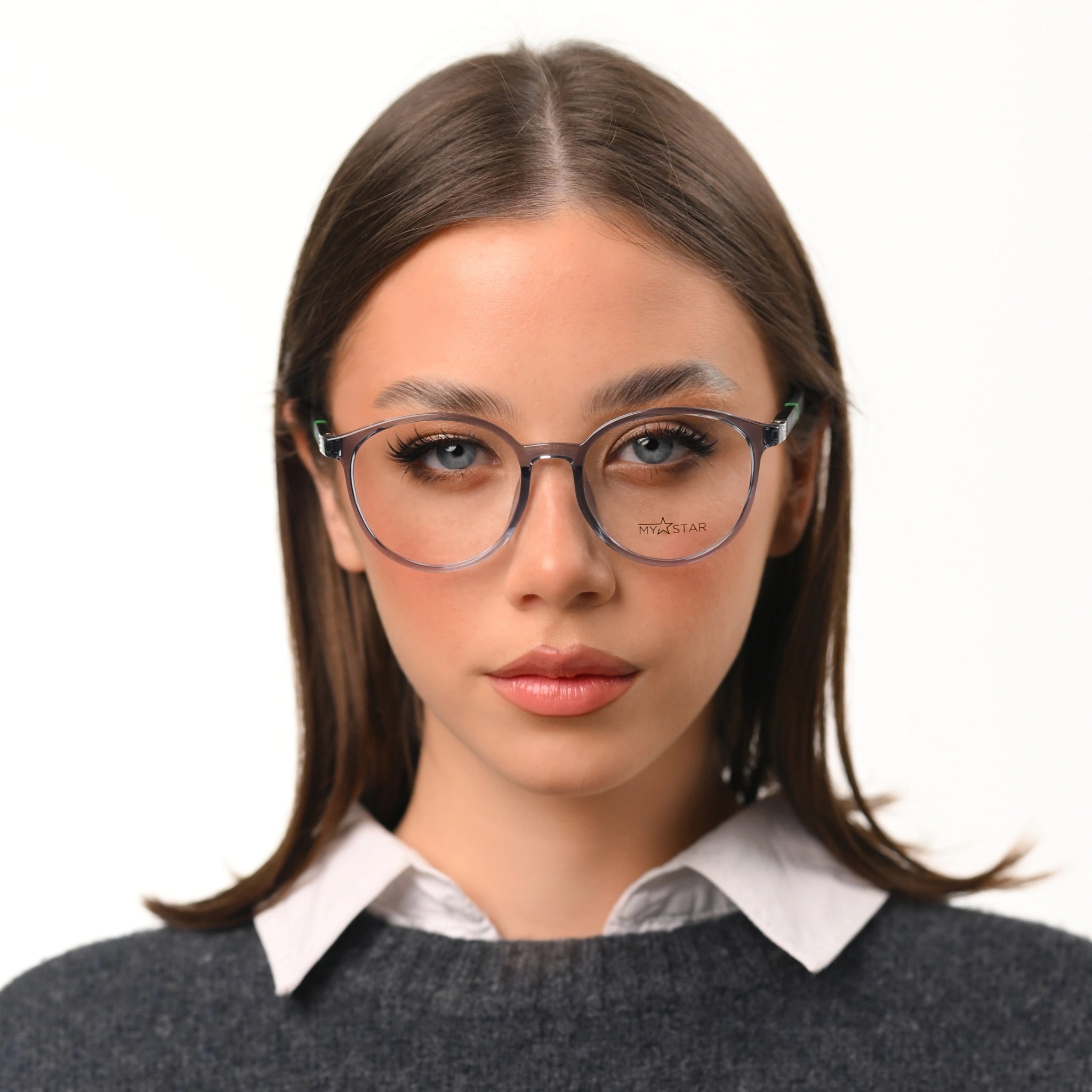 Woman wearing glasses with a white shirt and gray sweater on a white background