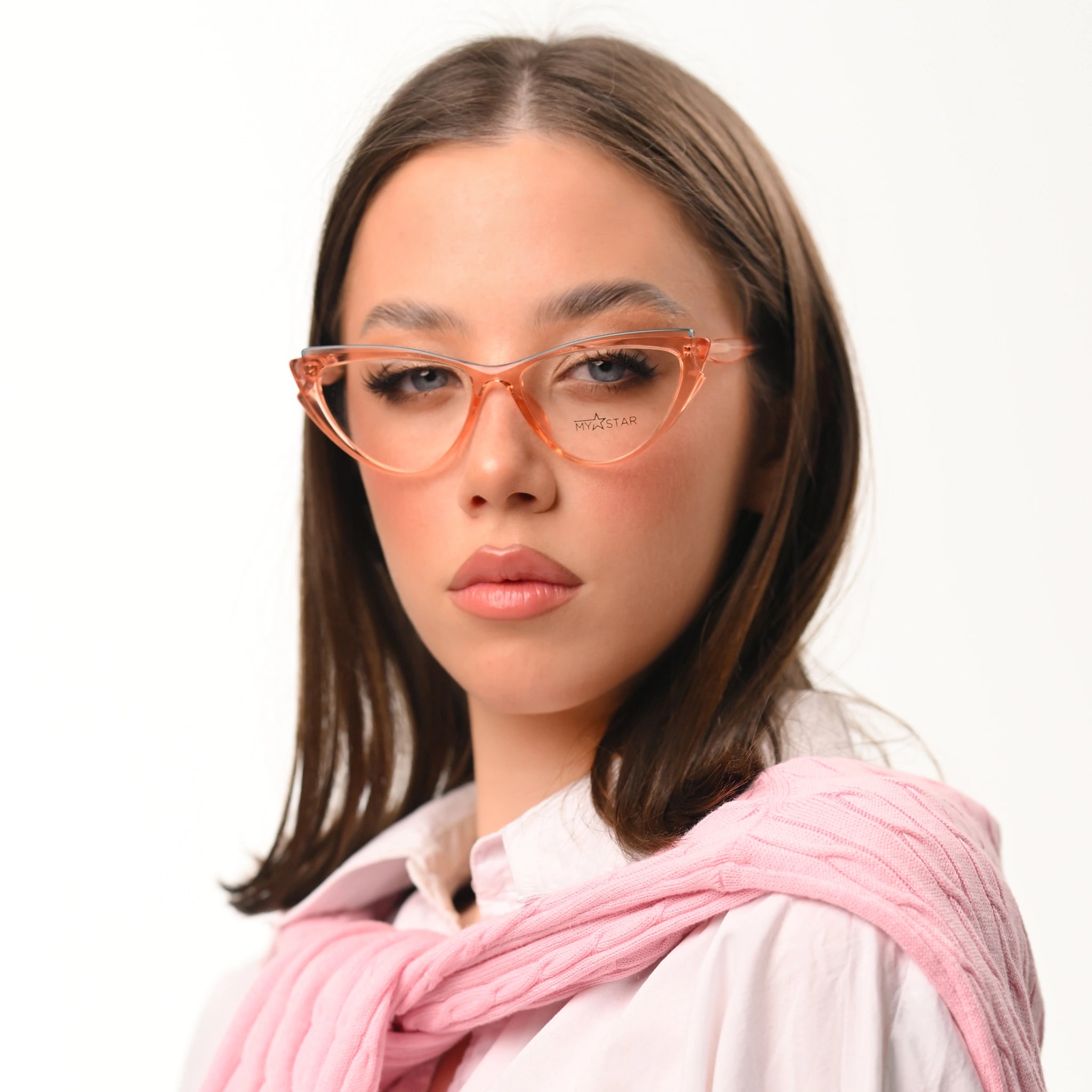 Woman wearing orange glasses and a pink scarf on a white background