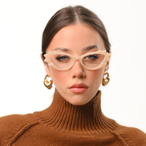 Woman wearing beige cat-eye glasses and a brown turtleneck sweater on a white background