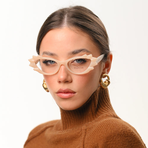 Woman wearing beige glasses and a brown turtleneck against a white background